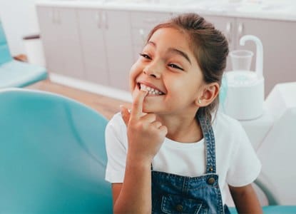 Happy young girl showing front teeth to dentist