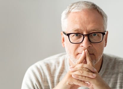 An older man covering his mouth.