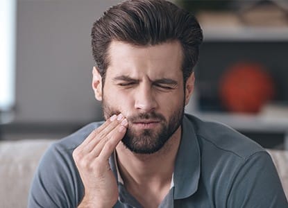 Man in pain holding cheek