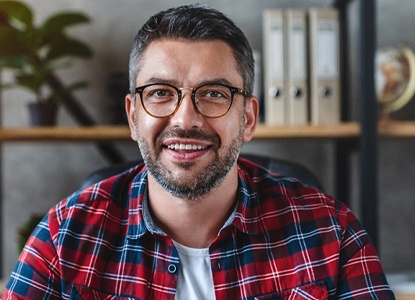 smiling person sitting in front of a bookshelf