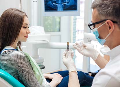 dentist showing a dental implant to a patient