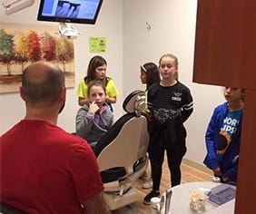 Dentist and young people in dental exam room