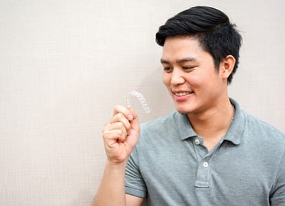 A man holding a clear aligner from Invisalign.