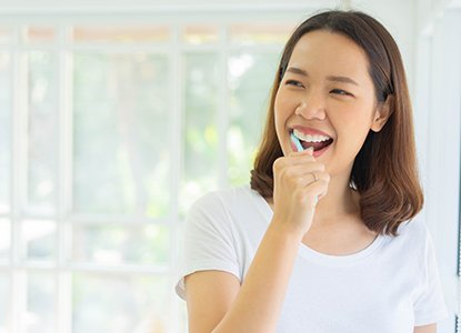 person smiling and brushing their teeth