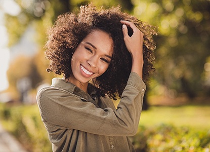 Closeup of woman with curly hair smiling with straight teeth