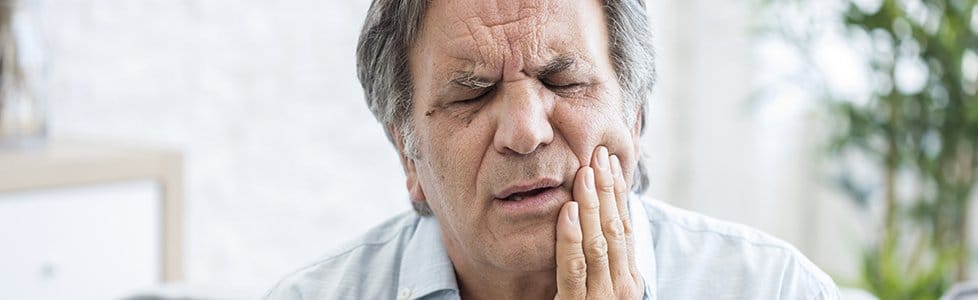 Older man holding jaw in pain